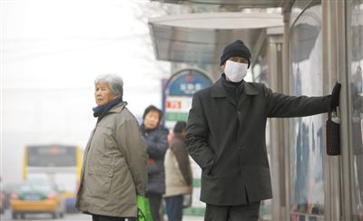 昨日，朝陽區延靜里，一位男子戴著口罩等公交車。本報記者 薛珺 攝